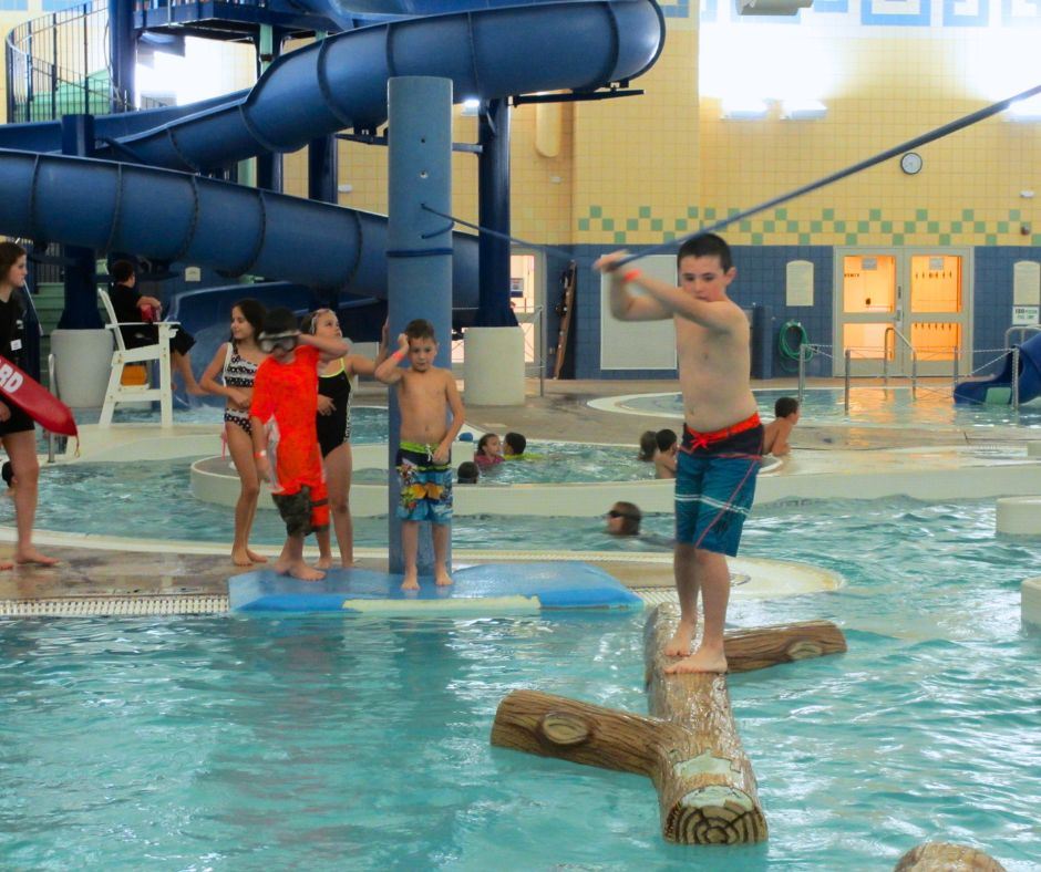 A boy tries to cross the log run while four kids wait on the other side for their turn.