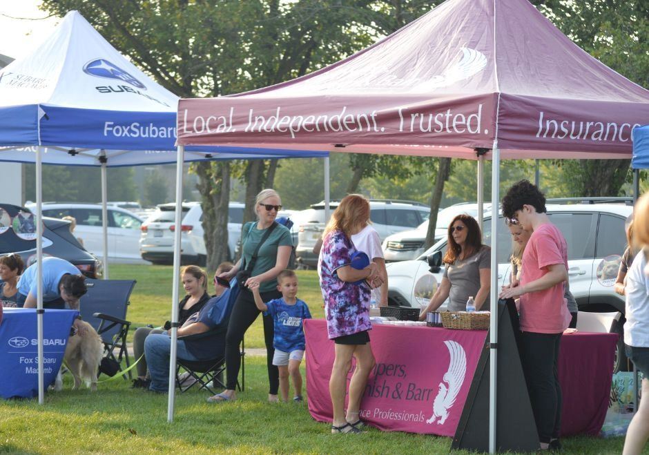 Sponsorship tent at an event. Sponsor staff are chatting with event patrons.