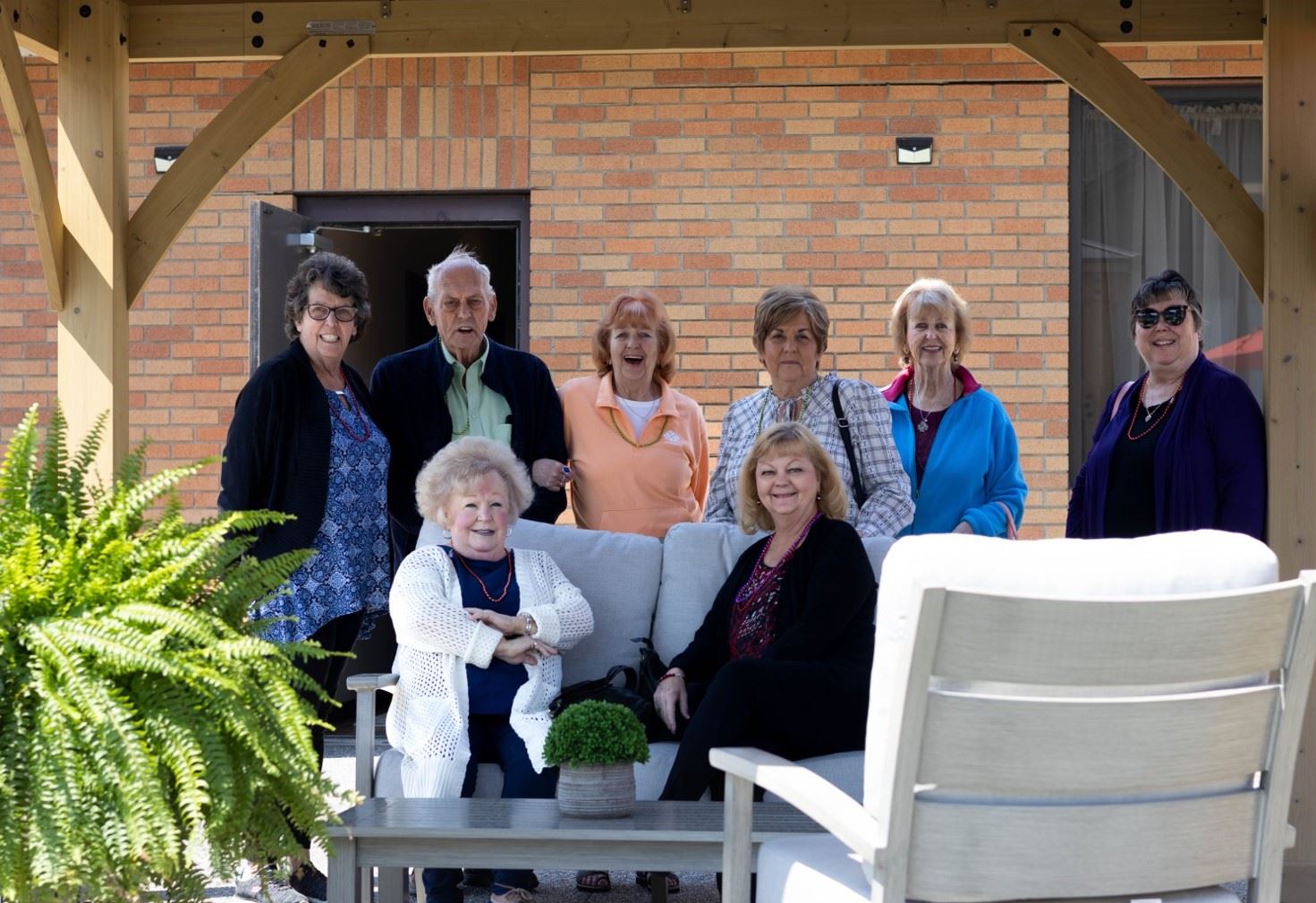Eight Senior residents smiling on the new senior center patio under a gazebo
