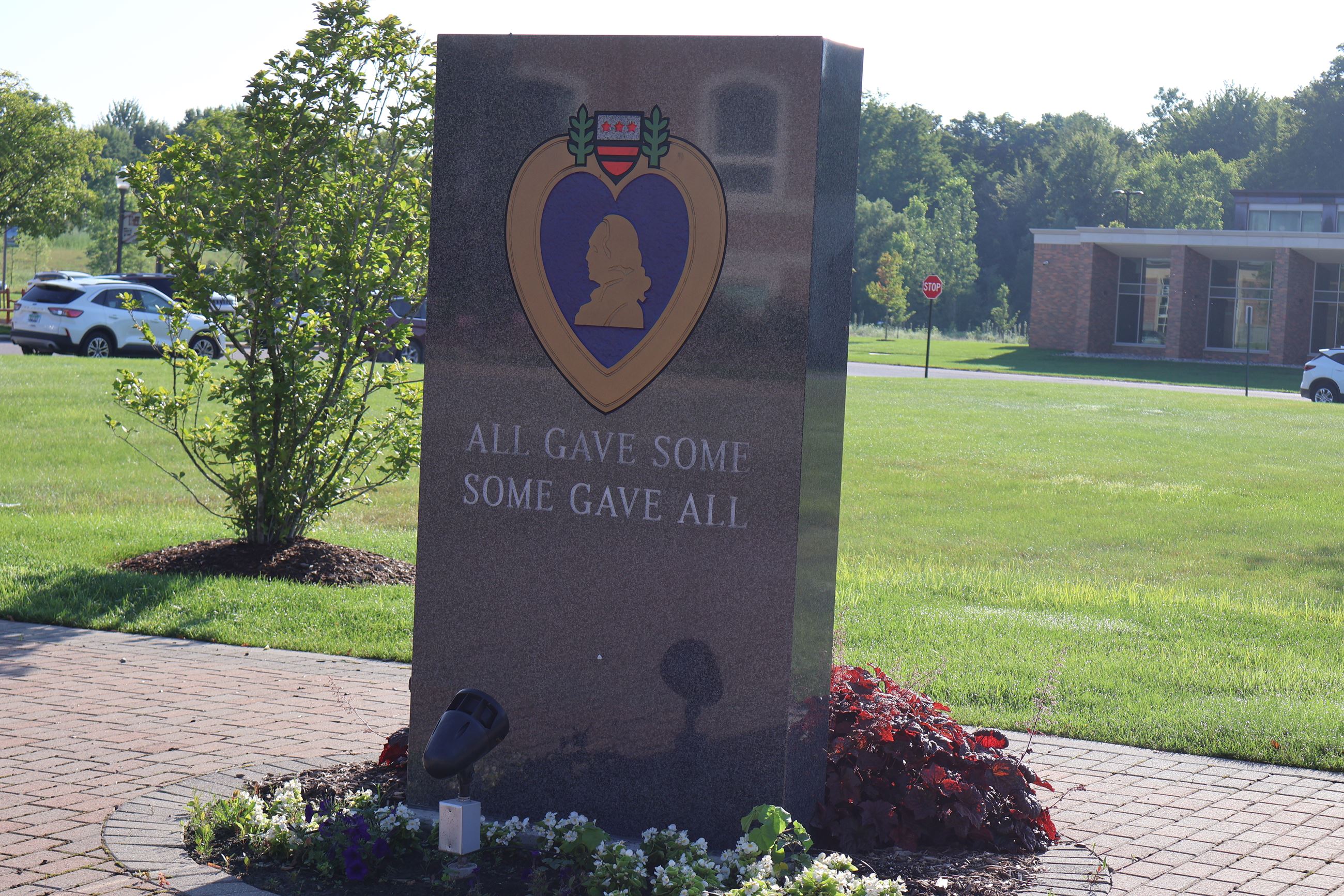 A stone monument with the Purple Heart metal engraved on its face.