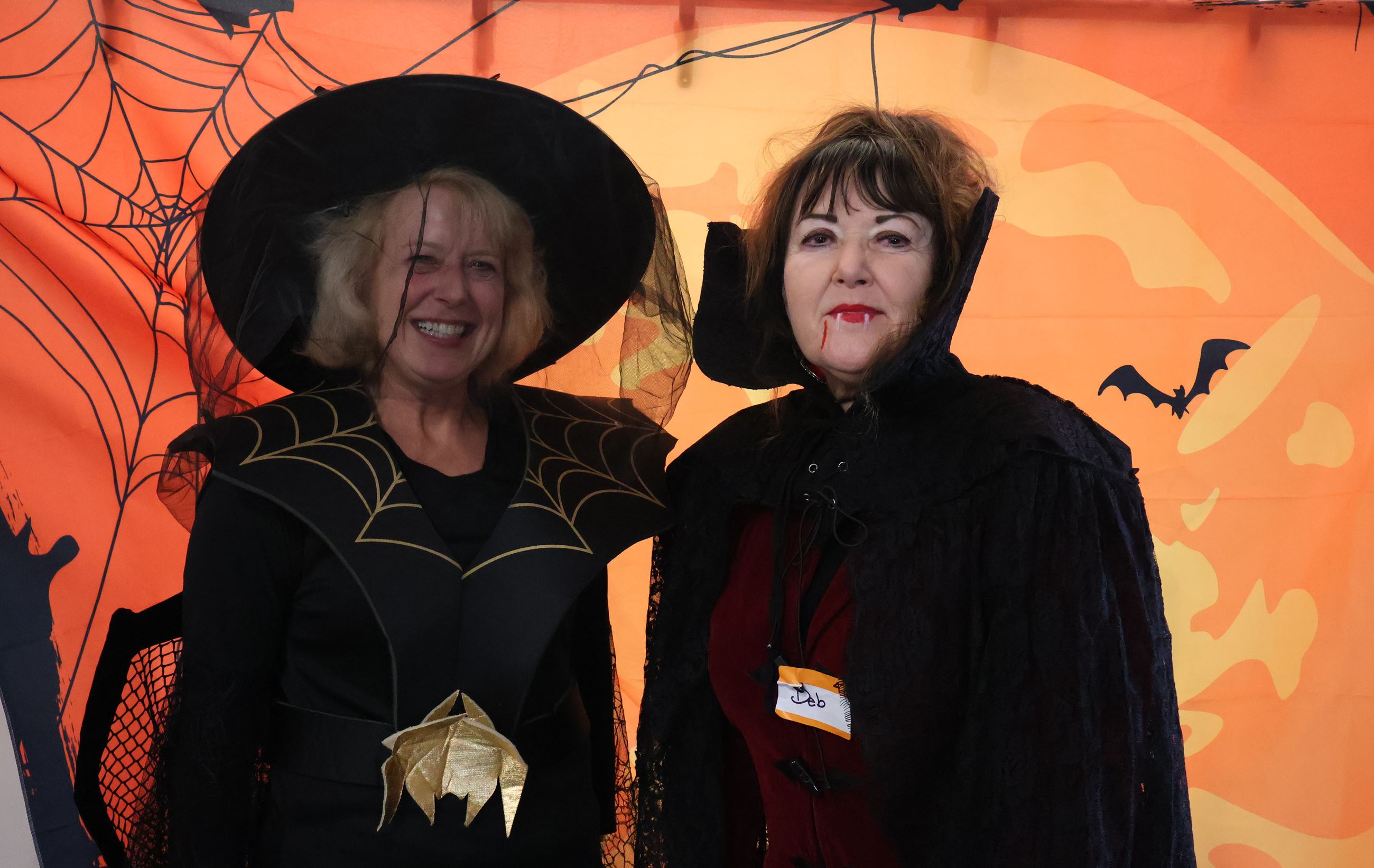 Two Seniors dressed up as vampires in front of an orange Halloween banner.